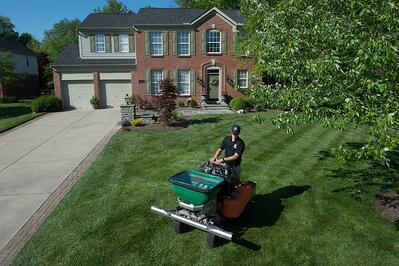 Landscaper applying seasonal lawn treatments